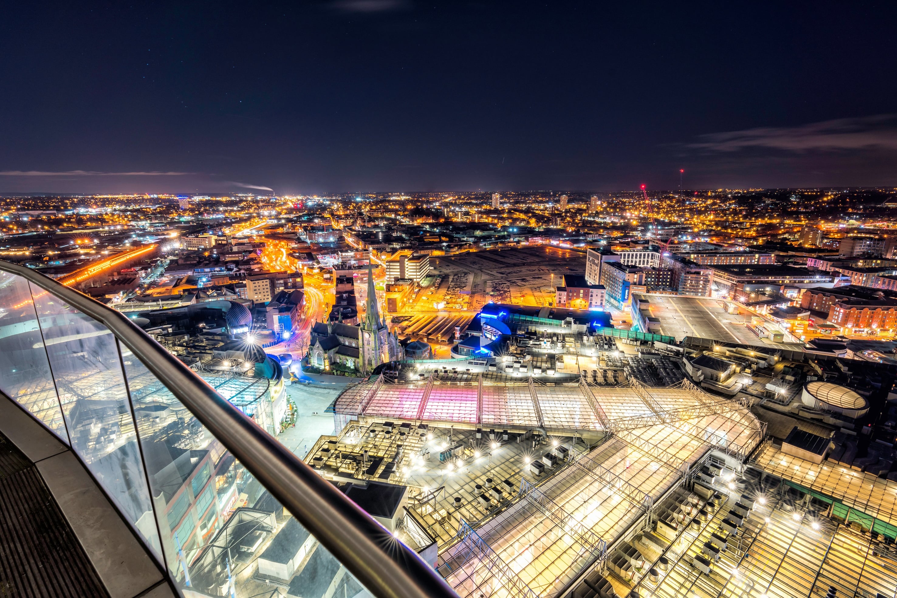 Birmingham city skyline at night viewed from the Rotunda, with illuminated buildings and streets